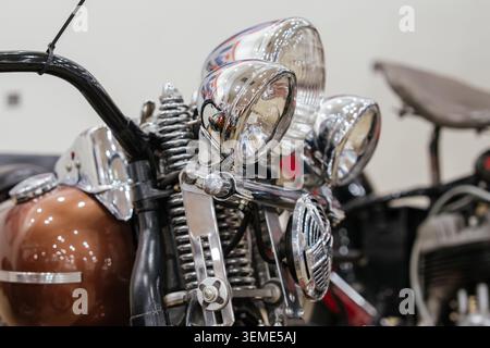 Vue détaillée de la section avant de la moto vintage, mettant en valeur les phares chromés et le guidon. Les ressorts chromés apparents soulignent la suspension classique Banque D'Images