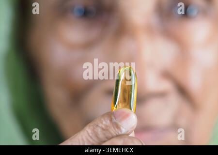 Femme âgée tenant une capsule d'huile de poisson dans un gros plan Banque D'Images