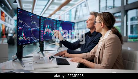 Focused Trader analyse plusieurs écrans d'actions pour prendre des décisions intelligentes. Banque D'Images
