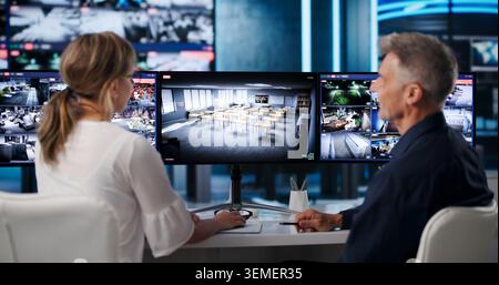 L'agent de sécurité et l'opérateur surveillent plusieurs écrans, surveillent les séquences en direct. Banque D'Images