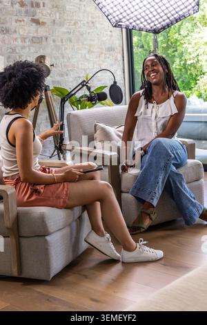 Animatrice de podcasts afro-américaines et invitée discutant dans le salon avec microphone sur perche Banque D'Images