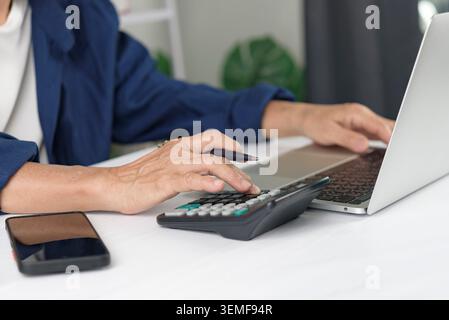 Gros plan des mains de femme senior utilisant la calculatrice et l'ordinateur portable pour la comptabilité. Planification budgétaire financière des personnes âgées, calcul des impôts et épargne-retraite Banque D'Images