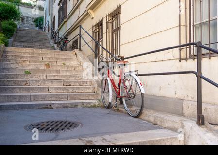Budapest, Hongrie – 2 mai 2026 : vélo appuyé contre des marches de pierre dans une rue résidentielle tranquille de Budapest Banque D'Images