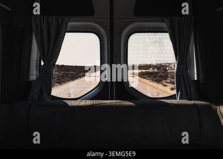 Vue à travers les vitres arrière du camping-car surplombant le paysage isolé de l'Outback et les voyages d'aventure sur la route de terre Banque D'Images