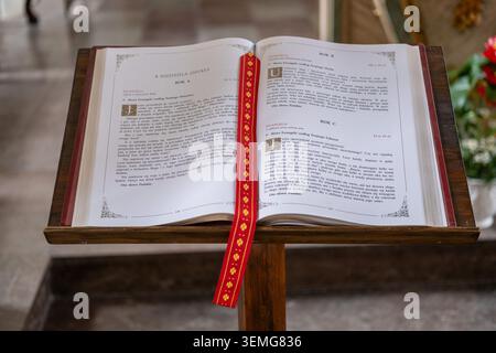 Livre lectionnaire ouvert avec texte polonais repose sur un stand de lecture en bois à l'intérieur d'un sanctuaire d'église. Banque D'Images