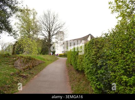Ronchamp, France – 17 avril 2015 : route menant vers la chapelle notre Dame du Haut par le Corbusier visible à flanc de colline en arrière-plan Banque D'Images