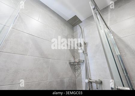 Salle de bains moderne salle de douche avec des murs de carrelage gris, une pomme de douche à effet pluie et une porte de douche en verre. Design épuré et minimaliste. Banque D'Images