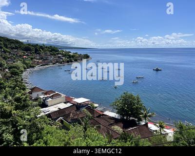 Vue aérienne du village de pêcheurs d'Amed avec des bateaux traditionnels Jukung dans une baie turquoise entourée de collines luxuriantes, Bali, Indonésie. Banque D'Images