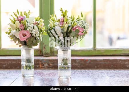 Bouquets de fleurs de mariage avec des roses roses et blanches dans des pots en verre décorés Banque D'Images