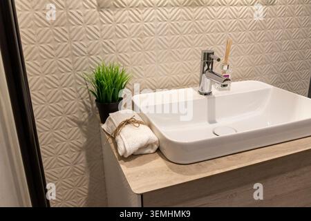 Décoration contemporaine des toilettes, évier en céramique et mur géométrique texturé Banque D'Images