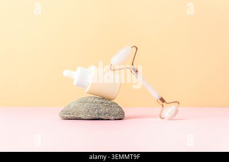 Composition minimale de soins de la peau avec bouteille de sérum et rouleau facial équilibré sur pierre sur fond pastel doux avec espace de copie. Banque D'Images