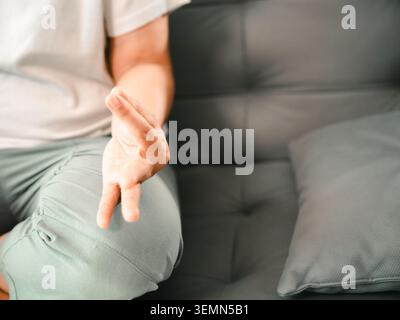 Gros plan d'une femme asiatique pratiquant un geste apaisant de la main assise sur un canapé à la maison, montrant la pleine conscience, la méditation, la relaxation, la respiration, Banque D'Images