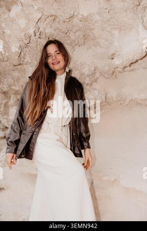 Femme grotte aventure jeune modèle élégant en veste en cuir posant contre des formations rocheuses sablonneuses dans la nature Banque D'Images