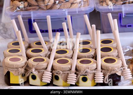 Petits pots de miel avec des plongeurs en bois enveloppés dans du papier artisanal au bazar de Tachkent. Authentique souvenir alimentaire biologique et concept d'emballage cadeau sain Banque D'Images