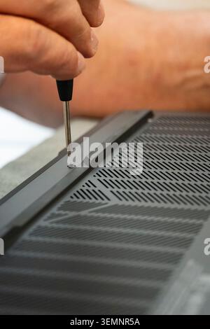 Gros plan d'une personne utilisant un tournevis pour retirer les vis du panneau arrière d'un ordinateur portable. Concept de maintenance informatique, réparation, mise à niveau et sup. Technique Banque D'Images