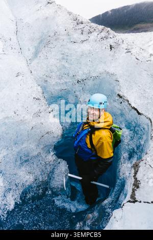 Homme dans le casque souriant dans le trou dans le glacier sur l'aventure en vacances Banque D'Images