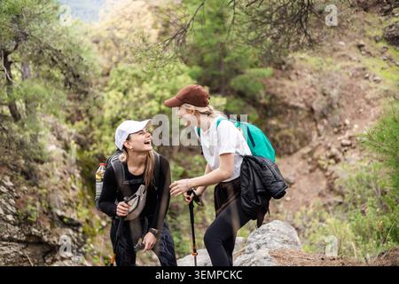 Deux jeunes amies rient ensemble en faisant une randonnée dans une forêt Banque D'Images