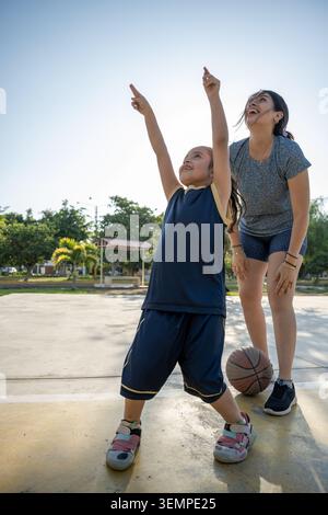 Mère et fille jouant sur un terrain de basket-ball extérieur Banque D'Images