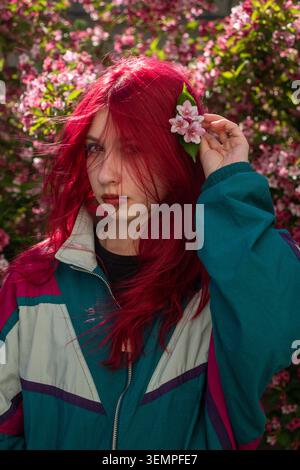 Jeune femme mettant une fleur rose dans les cheveux roux Banque D'Images