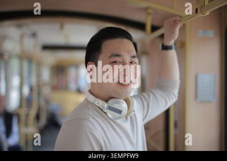 Heureux jeune homme asiatique dans les transports en commun Banque D'Images