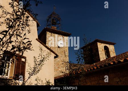 Une photo architecturale en angle bas des tours du village historique encadrées par des ombres de feuilles d'arbres en plein soleil. Banque D'Images