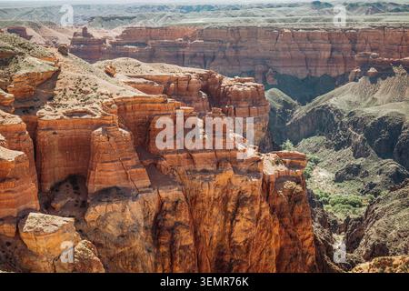 Vue panoramique époustouflante sur un gigantesque canyon rouge-orange avec de profondes gorges et des formations rocheuses superposées magnifiquement érodées sous la lumière du soleil Banque D'Images