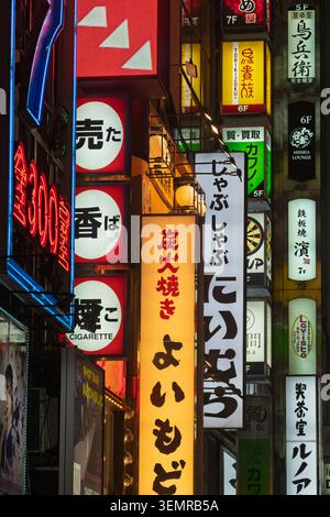 Vue en perspective étroite donnant sur une ruelle bordée de panneaux lumineux au néon la nuit, Shinjuku, Tokyo, Japon Banque D'Images