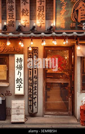 Bois vieilli, panneaux peints à la main et ampoules chaudes regroupés au-dessus de la porte d'un restaurant Shibuya, Tokyo, Japon Banque D'Images