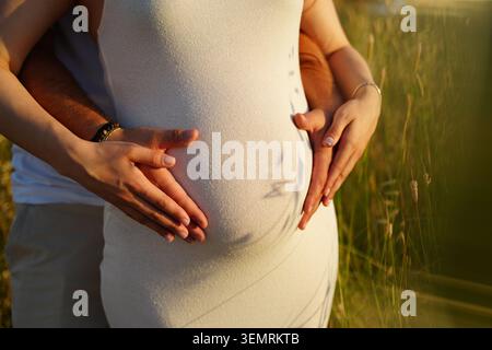 Couple d'attente embrassant le ventre enceinte à l'extérieur Banque D'Images