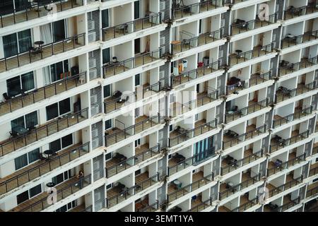 Une vue en grand angle capture le motif répétitif des balcons sur un immeuble résidentiel moderne. Il illustre une vie urbaine dense avec des détails subtils Banque D'Images