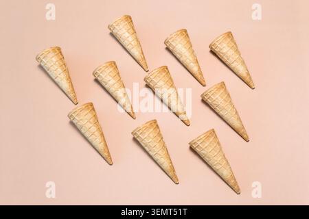 Cônes gaufrés disposés sur un fond beige dans une composition plate. Banque D'Images