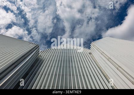 Perspective ascendante spectaculaire à faible angle regardant trois façades architecturales blanches modernes frappantes avec des panneaux de revêtement nervurés verticaux répétitifs, fra Banque D'Images