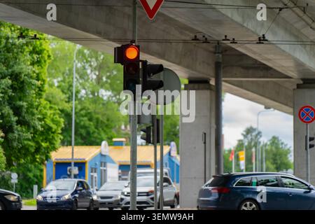 Carrefour de transport urbain comportant un système de feux stop fixé sur un poteau en acier sous une lourde structure de survol d'autoroute avec voiture active Banque D'Images