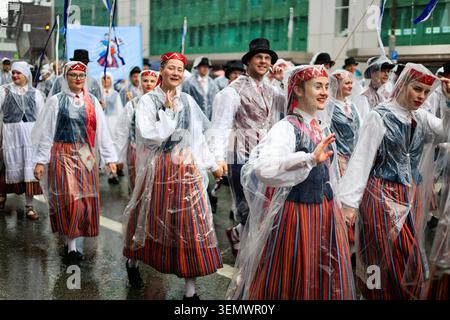 Participants souriants dans des costumes folkloriques estoniens colorés qui agitent pendant le défilé de la célébration de la chanson et de la danse. Tallinn, Estonie. 5 juillet 2025. Banque D'Images