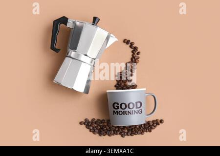 Pot de moka versant des grains de café dans une tasse Good Morning, café fraîchement infusé et concept de boisson de petit déjeuner, cette composition plate met en valeur le breakf Banque D'Images