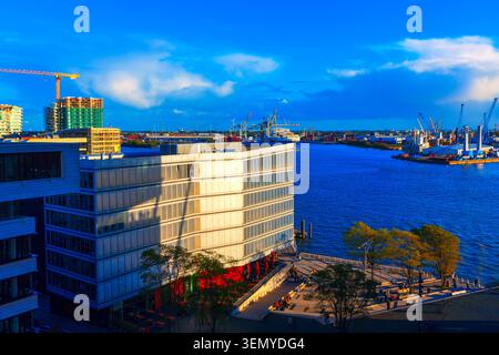Le quartier moderne de Hambourg HafenCity présente une architecture contemporaine en bord de port sur la pittoresque rivière Elbe. Les gens se détendent sur la promenade urbaine ensoleillée Banque D'Images