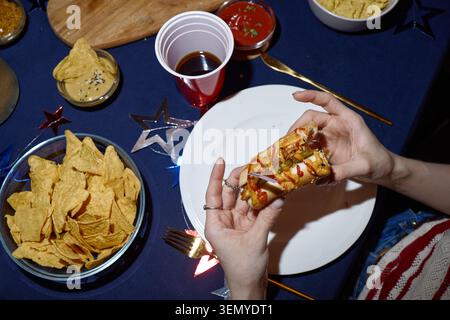 Femme adulte tenant Hot Dog pendant la fête du jour de l'indépendance à la maison Banque D'Images