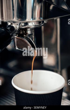 Espresso frais coulant du porte-filtre dans le gobelet en papier à emporter. Photo de haute qualité Banque D'Images