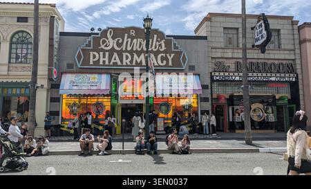 Schwab’s Pharmacy et les devantures de la chambre noire dans la rue animée sur le thème d’Hollywood à Universal Studios Japan, Osaka, avec des visiteurs qui se détendent. Banque D'Images