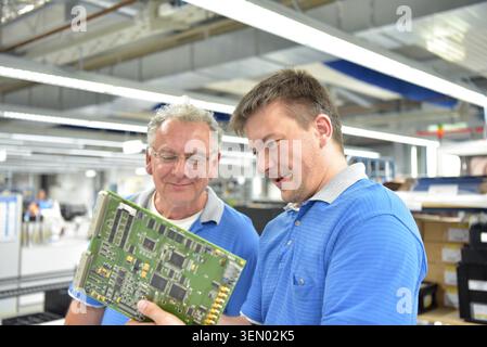 Travail d'équipe dans l'industrie - travailleur senior et jeune dans le département d'ingénierie d'une usine pour la production et la construction de l'électronique Banque D'Images