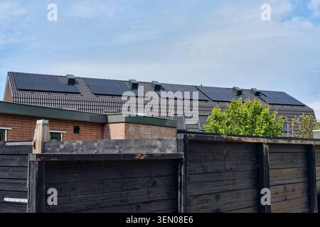 Solution d'énergie durable avec plusieurs panneaux solaires installés sur les toits de tuiles sombres des maisons résidentielles à Den Oever, pays-Bas. Banque D'Images