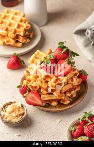 Délicieuses gaufres belges aux fraises et au miel sur plaque de céramique, fond de table beige. Délicieux petit déjeuner maison sucré. Vertical Banque D'Images