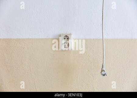 Cela capture une vieille prise électrique et un câble suspendu sur un mur usé dans un appartement délabré à Berlin, Prenzlauer Berg. Banque D'Images