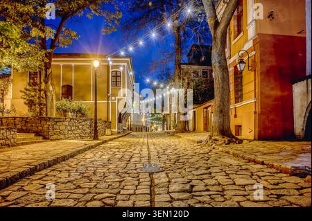 Une vue en angle bas de la rue Saborna dans la vieille ville de Plovdiv, Bulgarie, avec des façades illuminées du renouveau national et un pavé historique Banque D'Images