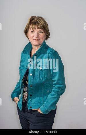 Jeanne Marie Laskas pose avec ses mains dans les poches d'une veste sarcelle. Elle a une expression détendue comme elle se tient sur un fond clair Banque D'Images