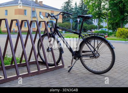 Supports de vélo classiques noirs fixés à un support en zigzag en métal brun sur un trottoir de rue de la ville. Parking de transport urbain écologique près du trottoir t Banque D'Images