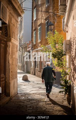 Un homme âgé descend Narrow Cobblestone Street dans la ville historique européenne Banque D'Images