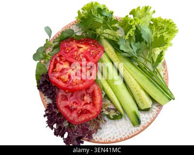 Tomates fraîches tranchées et concombre avec salades vertes mélangées sur une assiette Banque D'Images