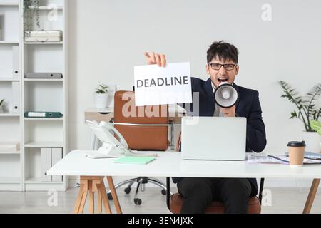 Homme d'affaires stressé criant message de délai par mégaphone dans le bureau, communication d'affaires urgente et gestion du temps Banque D'Images