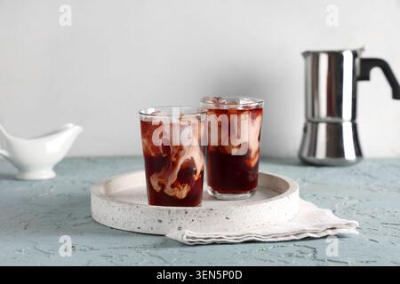 Deux boissons rafraîchissantes au café glacé avec des tourbillons de crème et des glaçons sur un plateau en terrazzo avec pot de moka, une serviette en lin blanc est placée sous les verres Banque D'Images